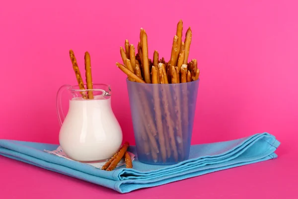 Palitos crocantes saborosos em copo de plástico roxo no fundo rosa — Fotografia de Stock