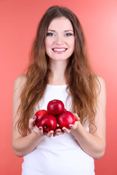 Vakker kvinne med epler på rosa bakgrunn – stockfoto