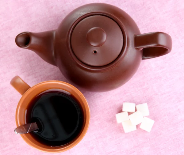 Vista superior de la taza de té y tetera en manteles rosas —  Fotos de Stock