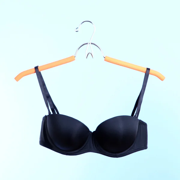 Elegant bra on hanger on blue background — Stock Photo, Image