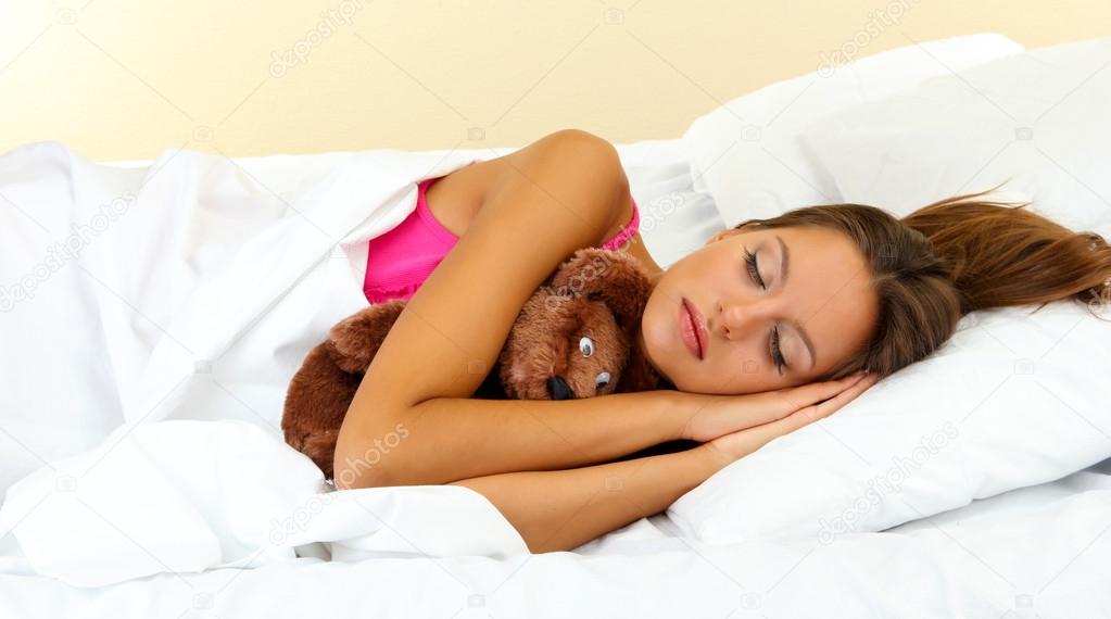 young beautiful woman sleeping with fluffy bear in bed