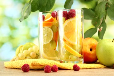 glasses citrus fruits and raspberries, on green background