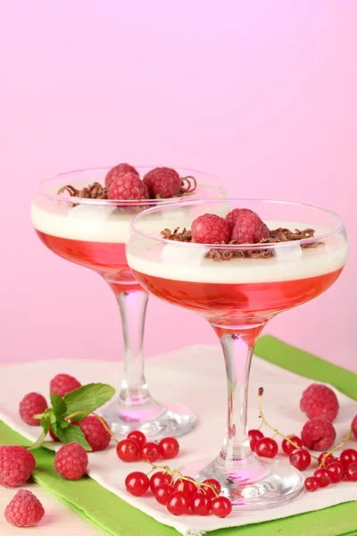 Фруктовое желе с ягодами в стаканах на деревянном столе на розовом фоне — стоковое фото