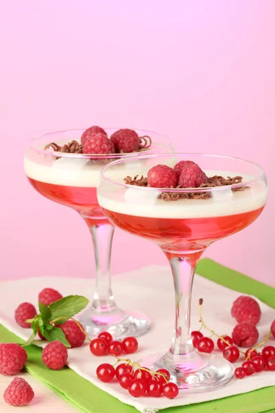 Gelée de fruits avec des baies dans des verres sur table en bois sur fond rose — Photo