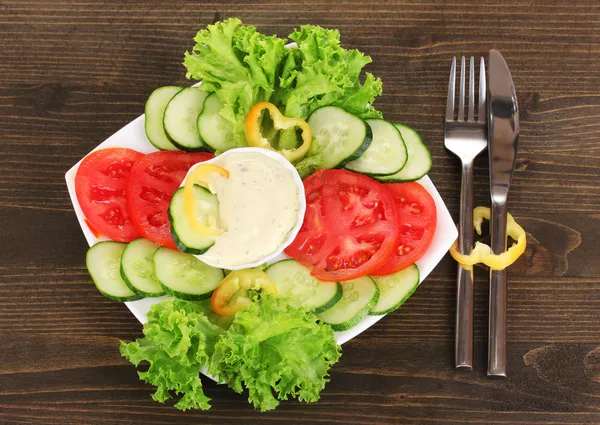 Gehakte groenten en saus op plaat op houten tafel — Stockfoto