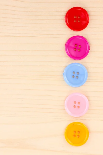 Цветные кнопки для шитья на деревянном фоне — стоковое фото
