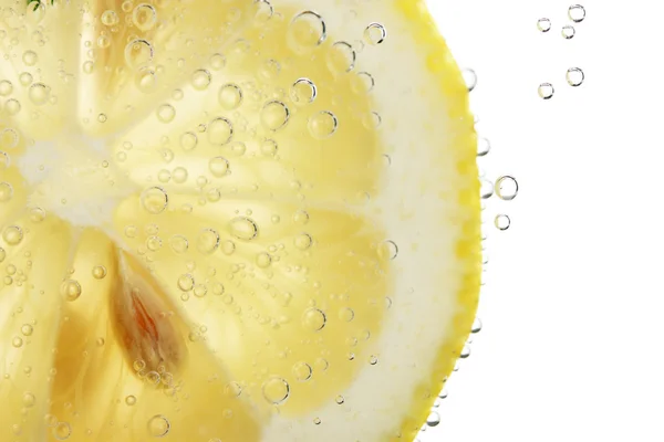 Zitronenscheibe im Wasser mit Blasen, isoliert auf weiß — Stockfoto