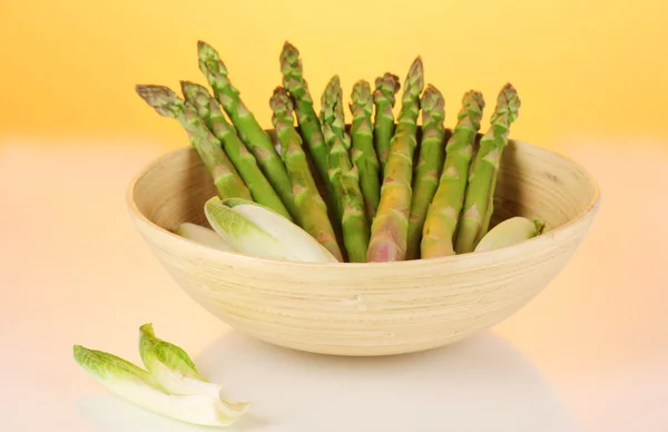 Fresh asparagus in wooden bowl on colorful background — Stock Photo, Image