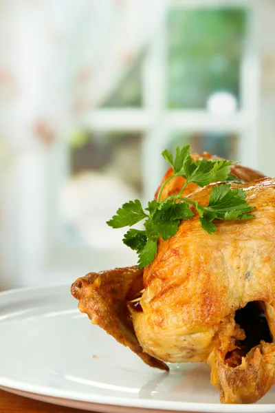 Frango inteiro assado em uma placa branca em fundo de madeira close-up — Fotografia de Stock