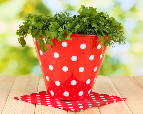 Red pot with parsley and dill on wooden table on natural background — Stock Photo, Image