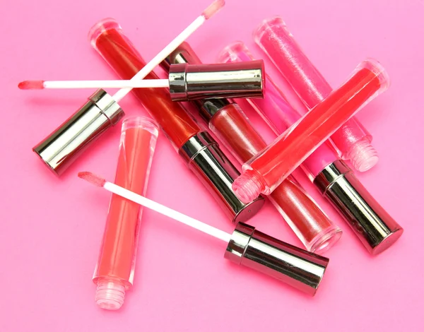 Hermoso brillo labial con pétalos de rosa, sobre fondo rosa —  Fotos de Stock