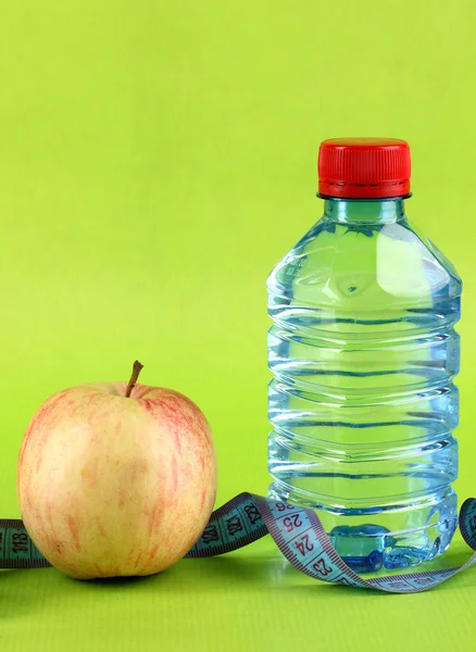 Flasche Wasser, Apfel und Maßband auf grünem Hintergrund — Stockfoto