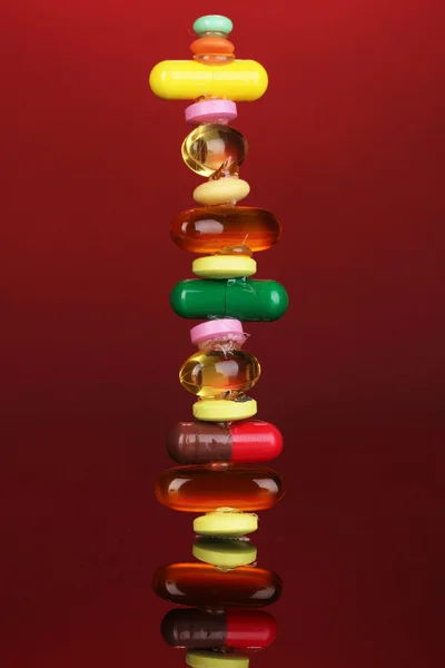 Kapseln und Pillen auf rotem Hintergrund — Stockfoto