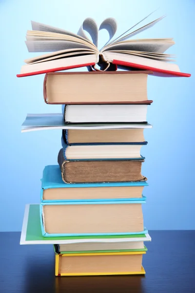 Стопка интересных книг и журналов на деревянном столе на синем фоне — стоковое фото