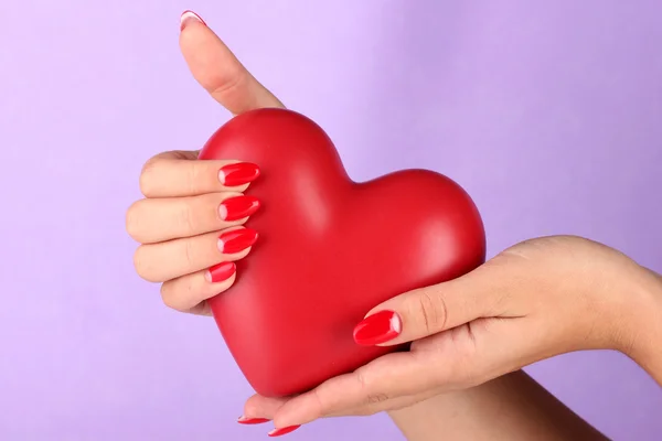 A női kéz a háttér színe piros szív — Stock Fotó