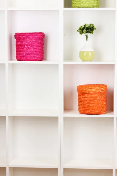 Цветные плетеные коробки на полках шкафов — стоковое фото