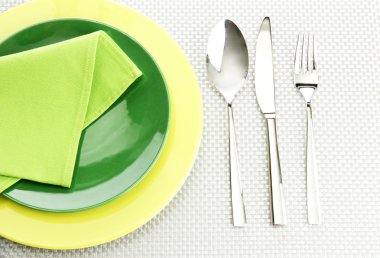 Yeşil boş tabak çatal, kaşık ve bıçak üzerinde gri bir masa örtüsü