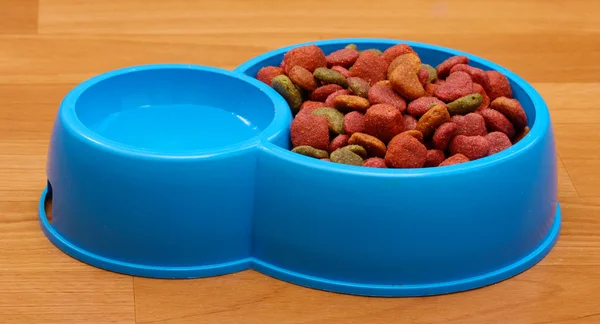 Dry dog food and water in blue bowl on the floor — Stock Photo, Image