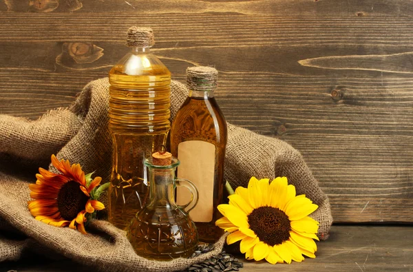 在瓶、 向日葵和种子、 木制背景上油 — 图库照片