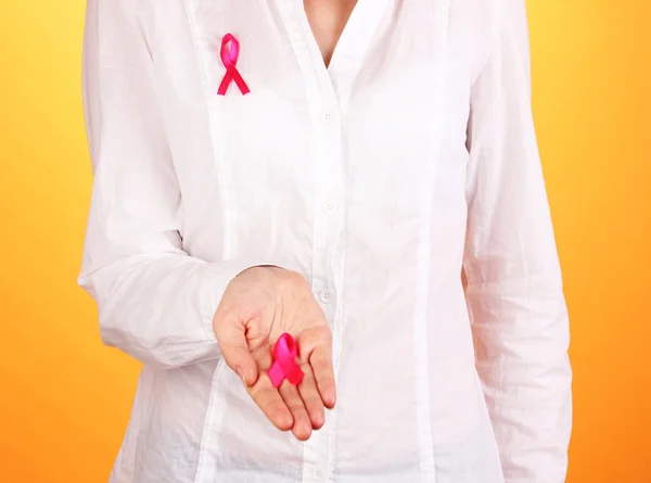 Vrouw met een roze lint in handen op oranje achtergrond — Stockfoto