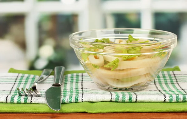 Salat aus Tintenfischringen, Zitrone und Salat in einer Glasschüssel auf einem Holztisch in Großaufnahme — Stockfoto