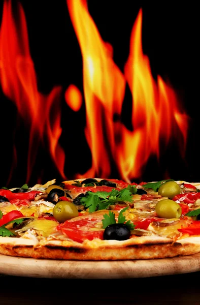 Leckere Pizza in Nahaufnahme auf Holztisch auf Feuer Hintergrund — Stockfoto