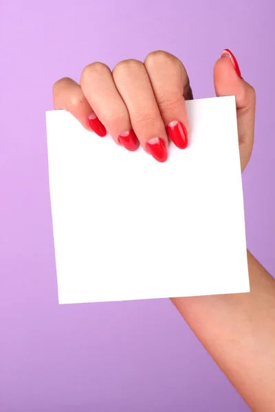 Mano della donna che tiene carta bianca su sfondo a colori — Foto Stock