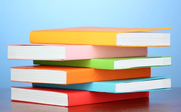 Pila di libri multicolore su sfondo blu — Foto Stock