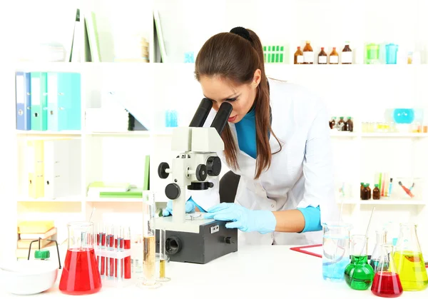看着显微镜在实验室中的青年科学家 — 图库照片