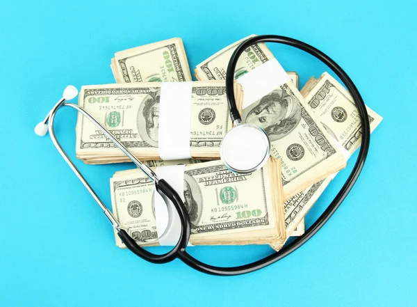 Healthcare cost concept: stethoscope and dollars on blue background — Stock Photo, Image