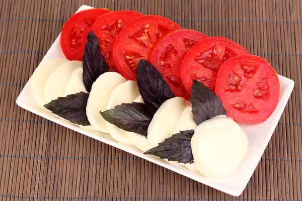 Mozzarella savoureux avec tomates sur assiette sur tapis — Photo