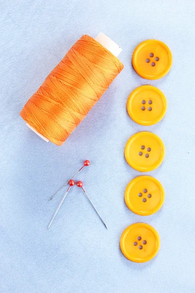 Botões de costura coloridos com fio em tecido azul — Fotografia de Stock