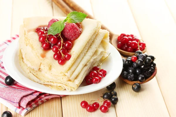 Pancake lezat dengan buah beri dan selai di piring di atas meja kayu — Stok Foto