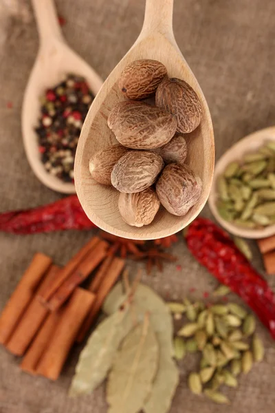 Nutmeg and other spices on sackcloth background — Stock Photo, Image