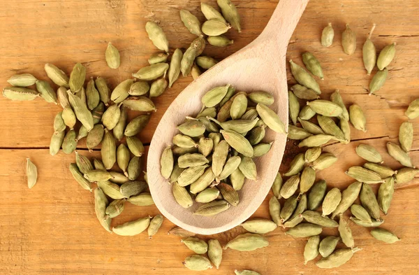 Cardamomo verde en cuchara de madera sobre fondo de madera —  Fotos de Stock