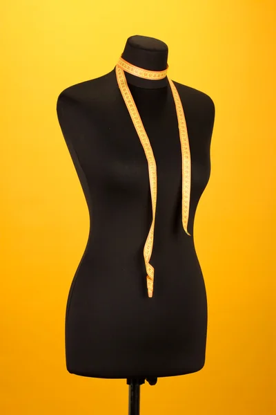 Empty black mannequin with measuring tape on orange background — Stock Photo, Image