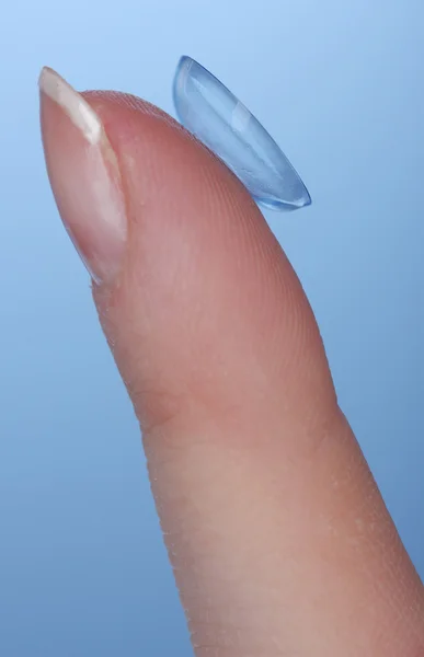 Contact lens on finger on blue background — Stock Photo, Image