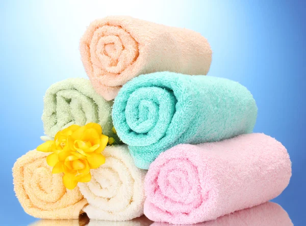 Kolorowe ręczniki i kwiaty na niebieskim tle — Zdjęcie stockowe