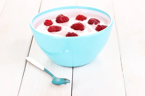 Yogurt with raspberries in bowl on wooden background — Stock Photo, Image