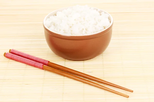 Cuenco de arroz y palillos en estera de bambú — Foto de Stock