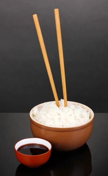 Bowl of rice and chopsticks on grey background — Stock Photo, Image