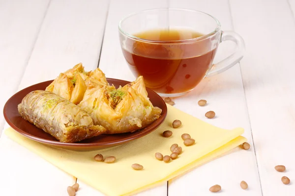 Dolce baklava su piatto con tè su sfondo di legno — Foto Stock
