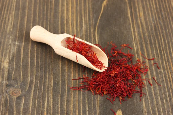 Stigmas of saffron in wooden spoon on wooden background close-up — Stock Photo, Image