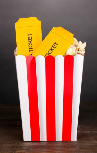 Popcorn mit Eintrittskarten auf Holztisch auf grauem Hintergrund — Stockfoto