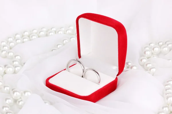 Anillos de boda en caja roja sobre fondo de tela blanca — Foto de Stock