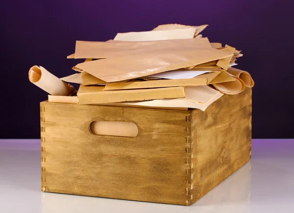 Caisse en bois avec papiers et lettres sur fond violet — Photo