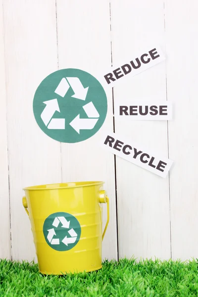 Reciclagem bin na grama verde perto de cerca de madeira — Fotografia de Stock