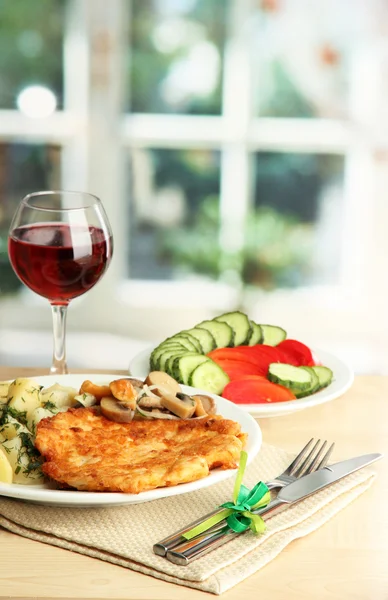 Roast chicken cutlet with boiled potatoes and vegetables, glass of wine on wooden table in cafe interior — Stock Photo, Image