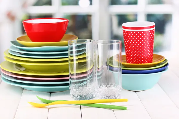 Colorful tableware on wooden table on window background — Stock Photo, Image