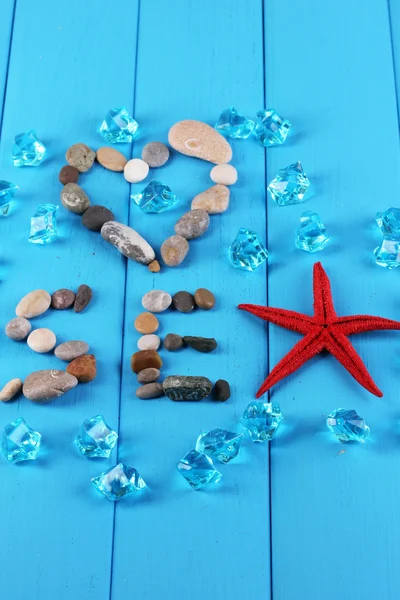 The word sea and decor of seashells close-up on blue wooden table — Stock Photo, Image